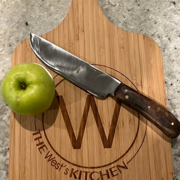 A hand-forged knife with a wooden handle on a cutting board