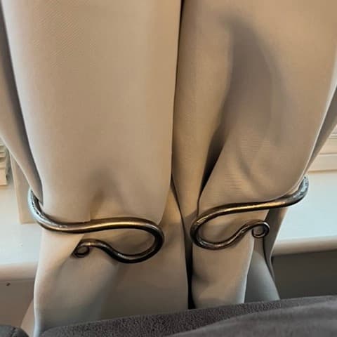 A pair of forged scrollwork curtain tiebacks